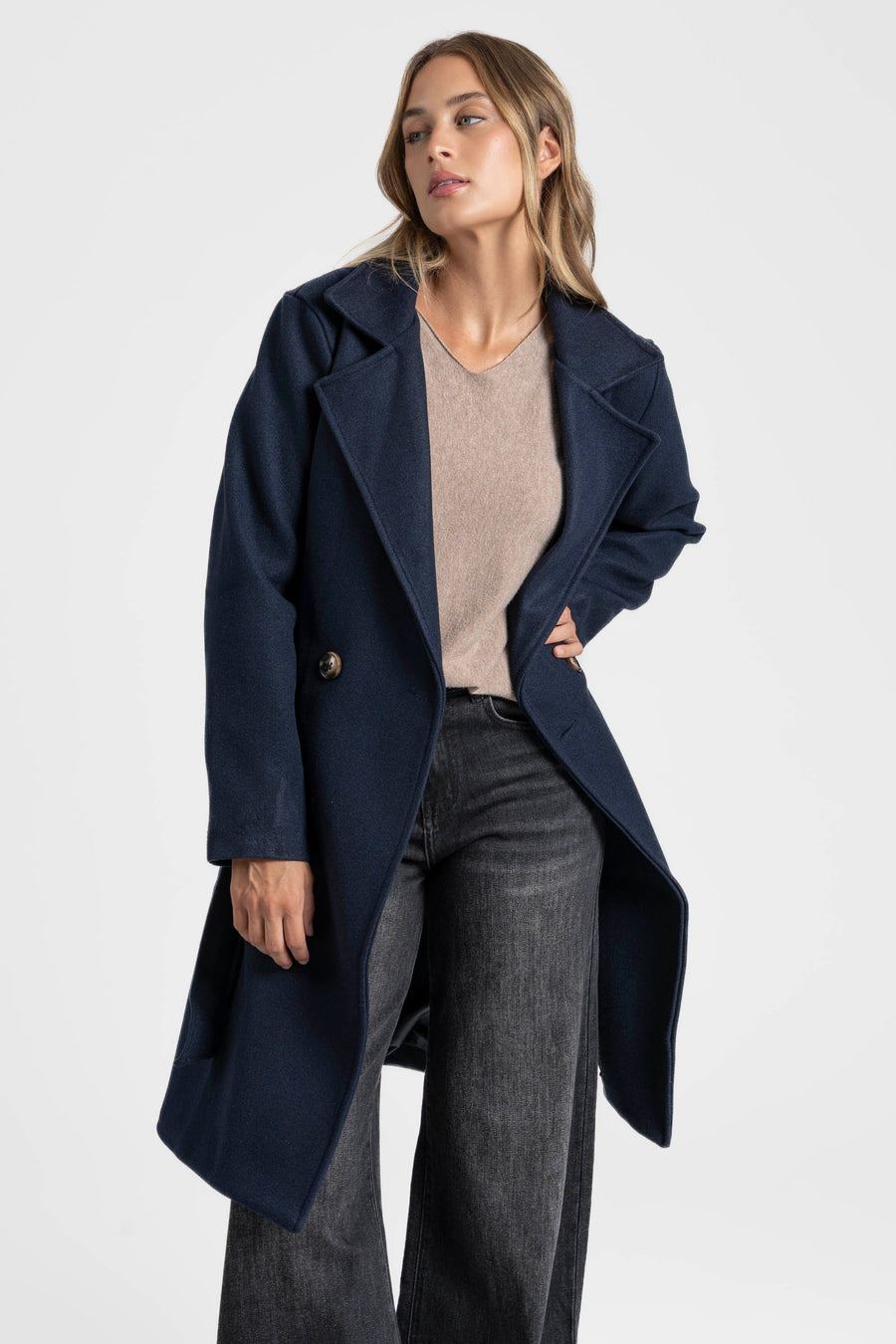 Manteau bleu marine ouvert, vue de trois quarts avec une main à la taille