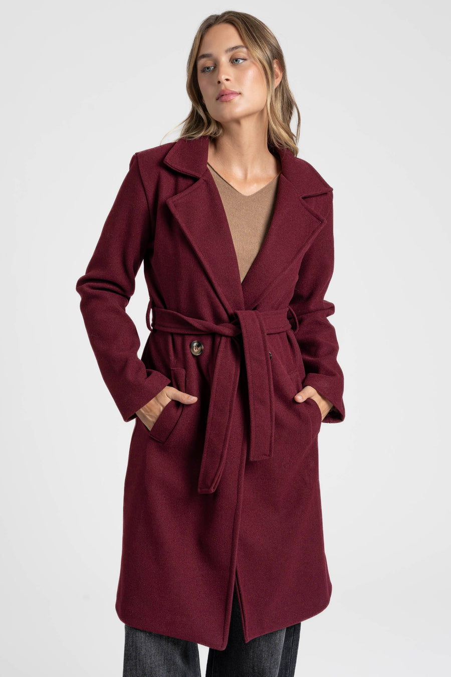Manteau bordeaux ceinturé, vue de face avec les mains dans les poches