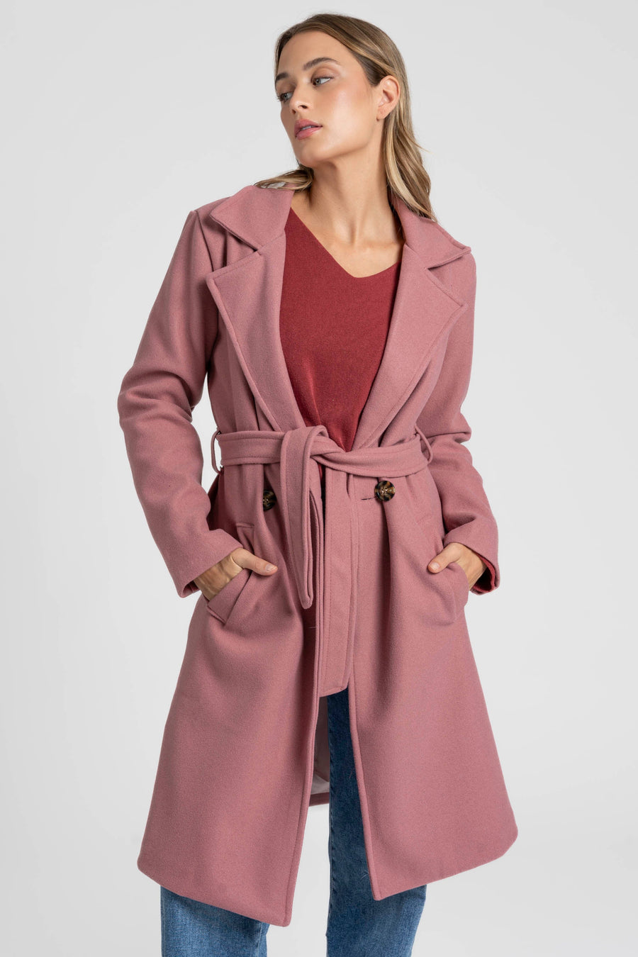 Manteau rose fermé par une ceinture nouée, détail du col et des poches