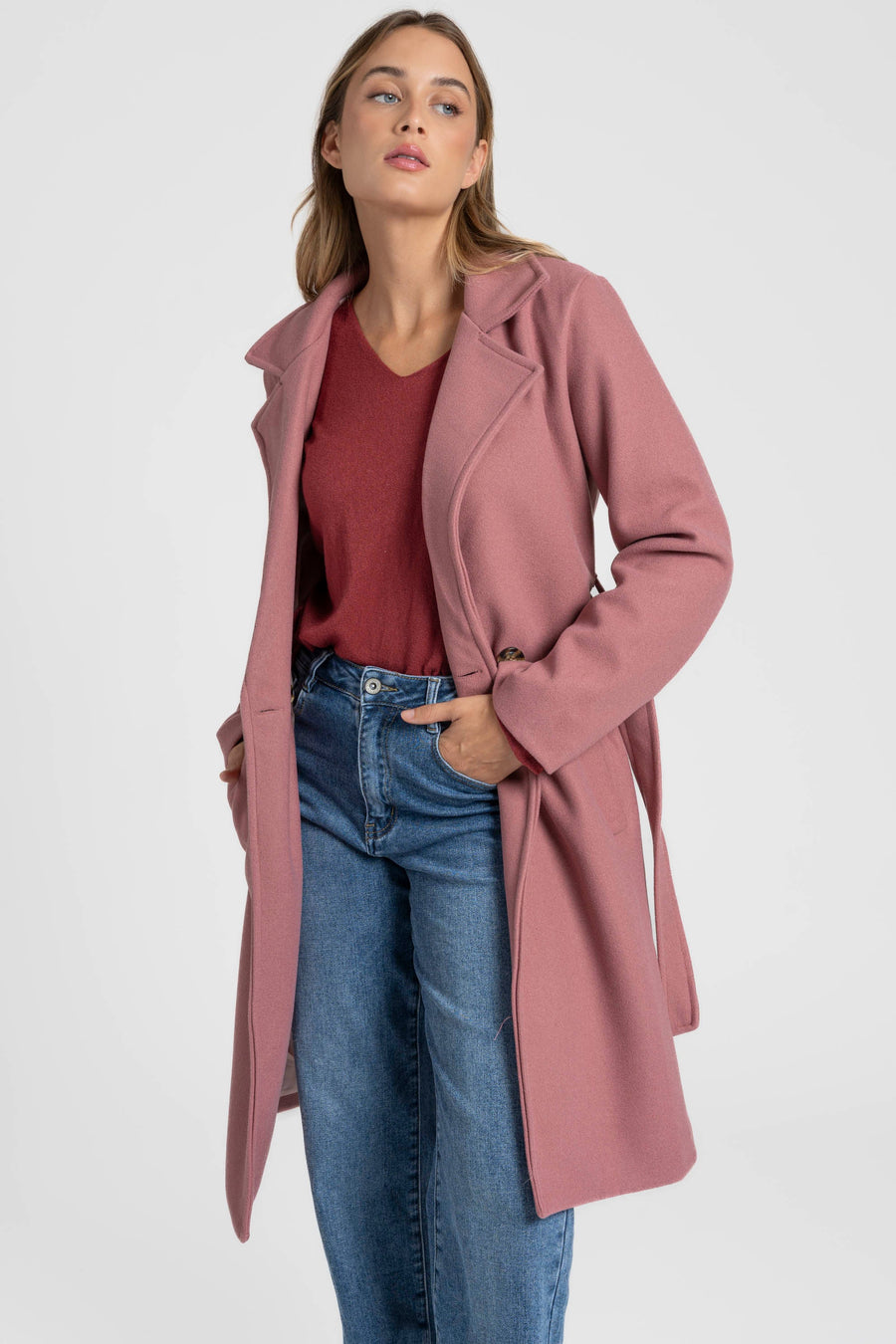 Manteau rose ouvert sur un haut bordeaux et un jean, vue de trois quarts
