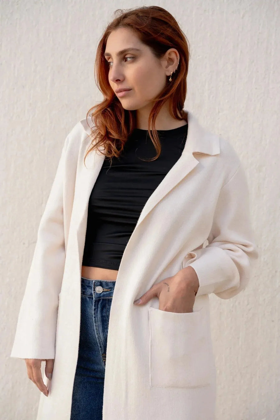 Femme portant un cardigan maille oversize cosy chic, avec un manteau en drap de laine, associé à un crop top noir et jean. Idéal pour un look élégant.