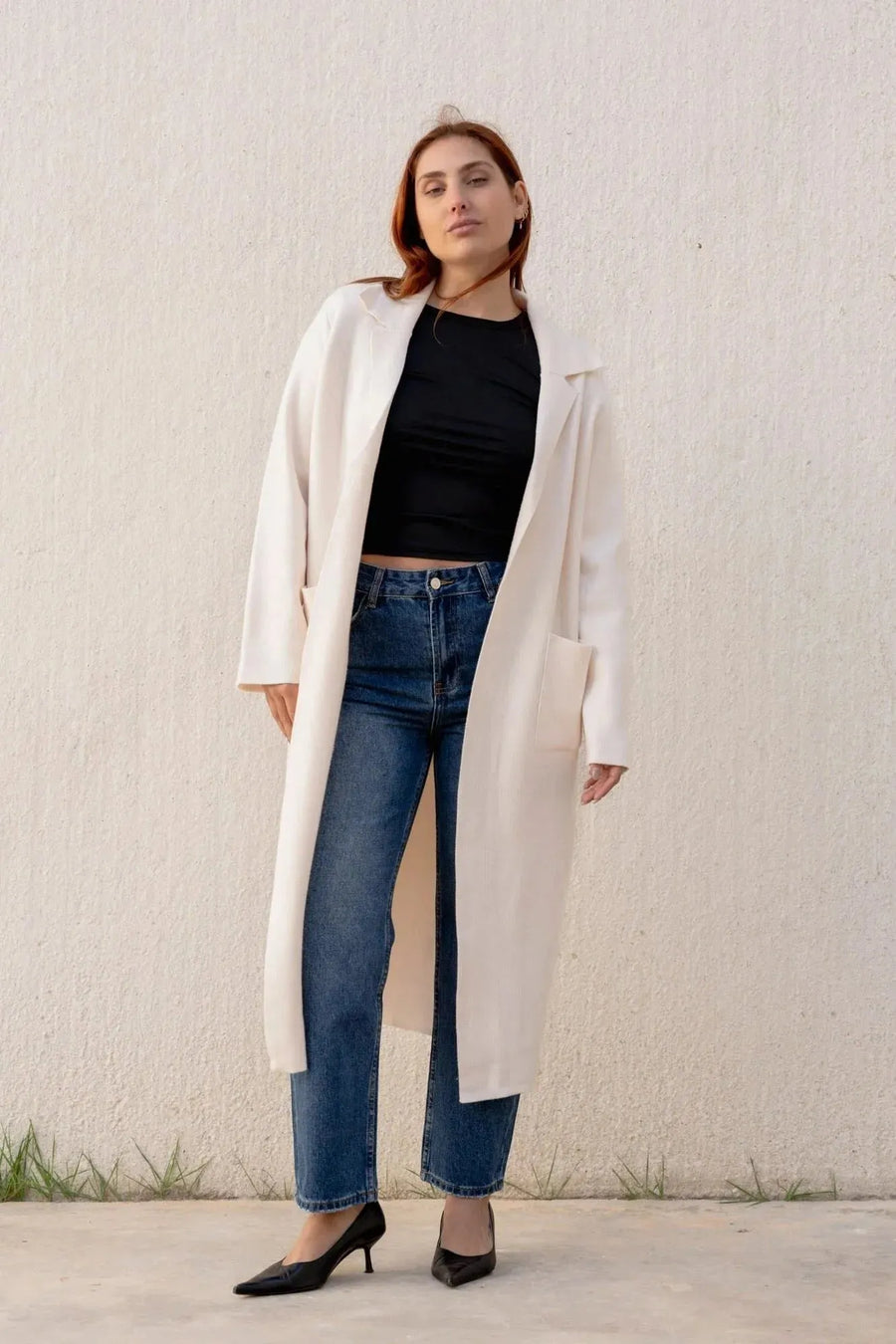 Modèle féminin en cardigan maille oversize cosy chic, mettant en avant un manteau en drap de laine, style décontracté avec un jean et des escarpins.