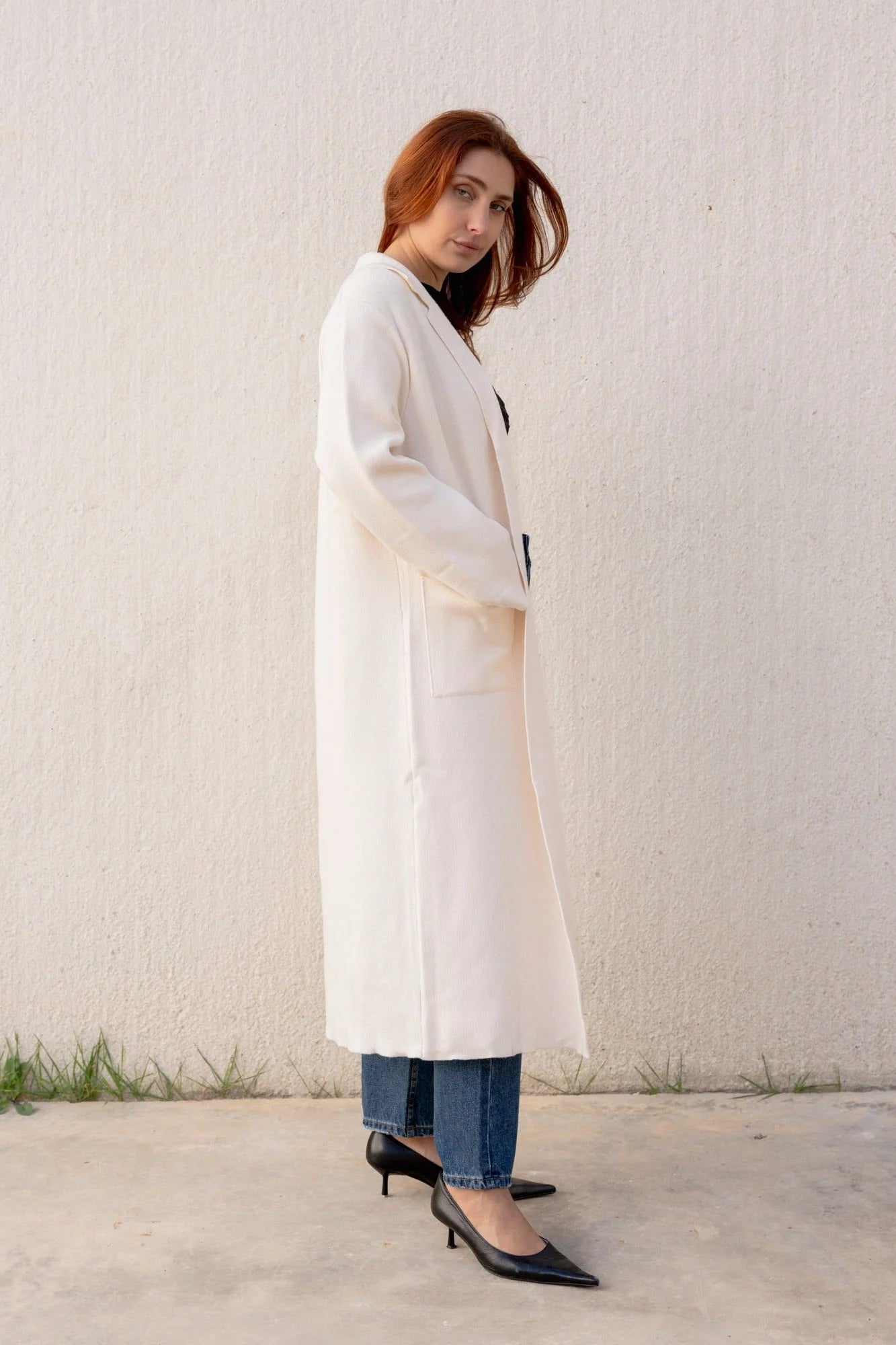 Femme posant avec un cardigan maille oversize cosy chic et un manteau en drap de laine, look chic et moderne, parfait pour les journées fraîches.