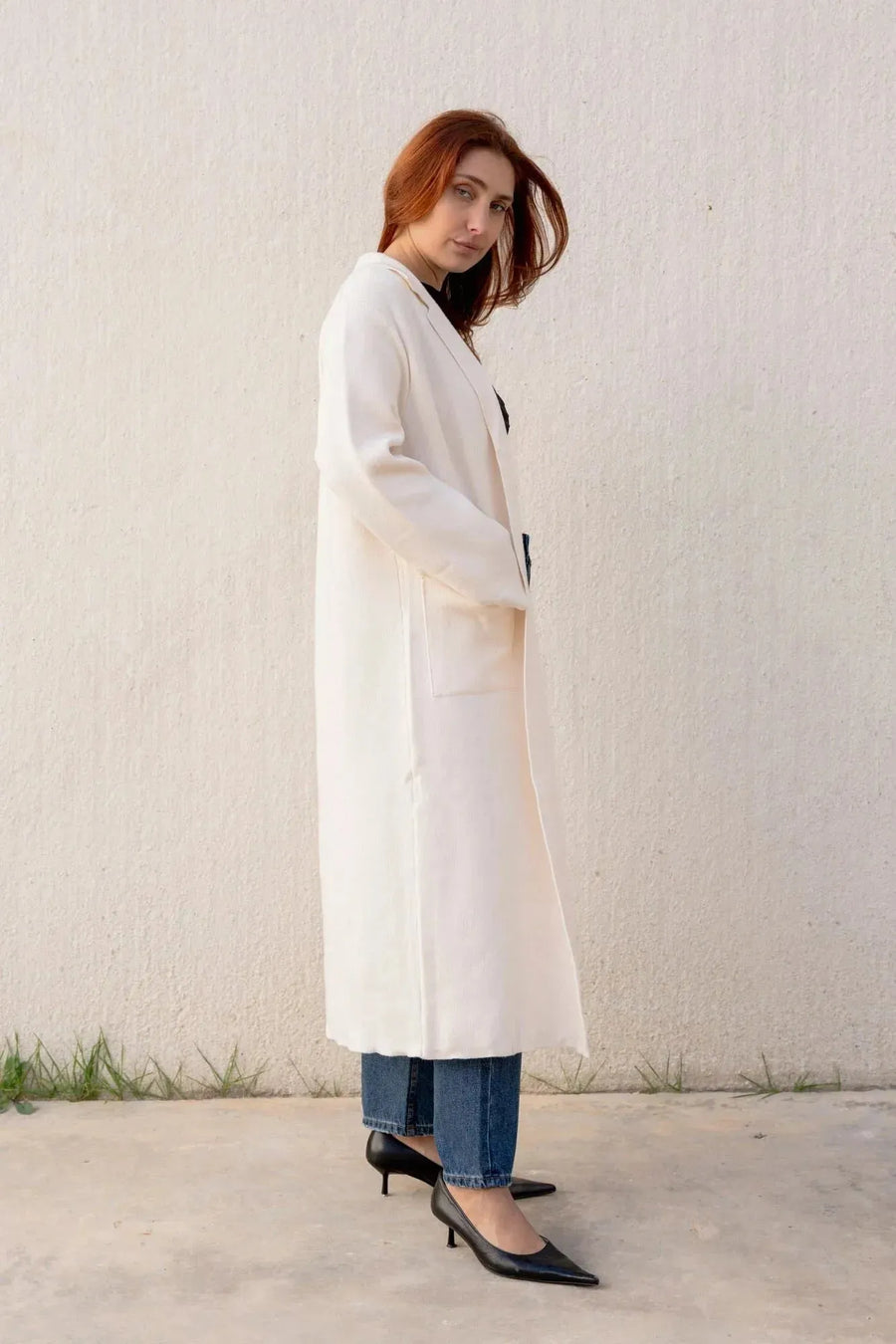 Femme posant avec un cardigan maille oversize cosy chic et un manteau en drap de laine, look chic et moderne, parfait pour les journées fraîches.