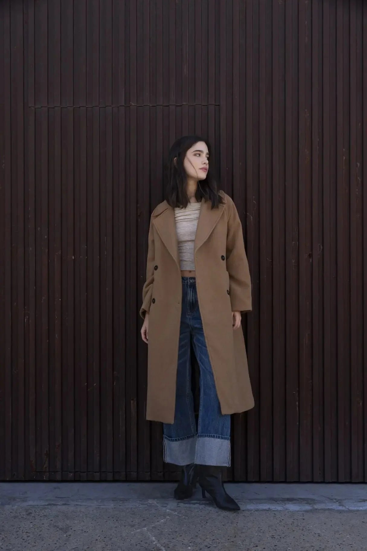 Femme en manteau camel avec col revers, crop top clair, jeans wide-leg et bottines noires