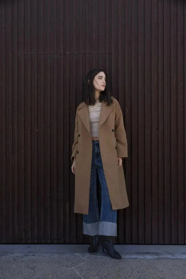 Femme portant un manteau long en laine double boutonnage camel, parfait pour l'hiver, mettant en valeur le manteau femme hiver long.