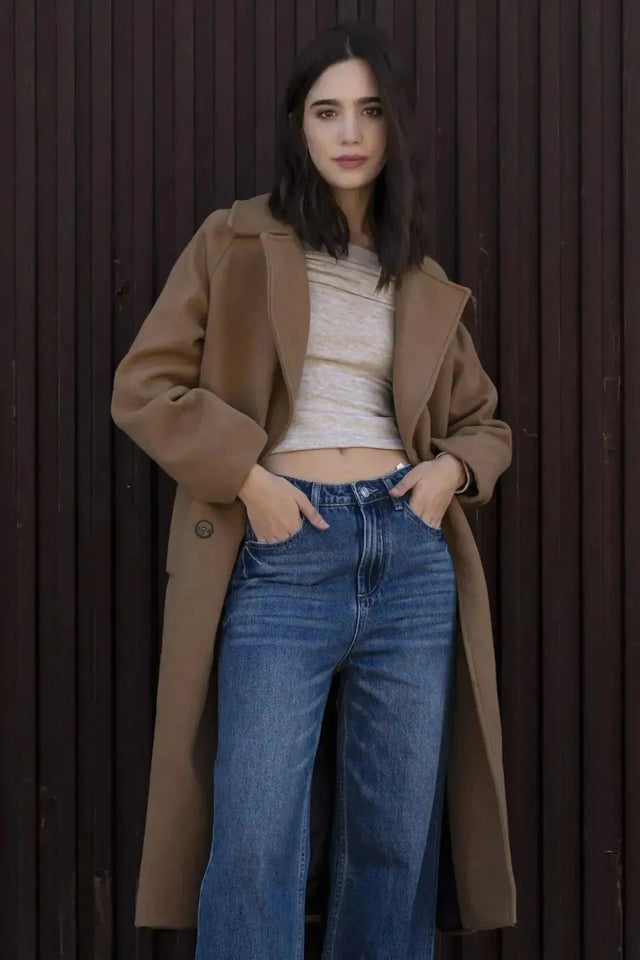 Détail d'une femme avec un manteau long en laine camel, épouse parfaitement le style chic et chaleureux du manteau femme hiver long.