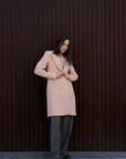 Modèle ajustant le manteau beige femme long élégant, idéal pour un look chic et confortable en hiver.
