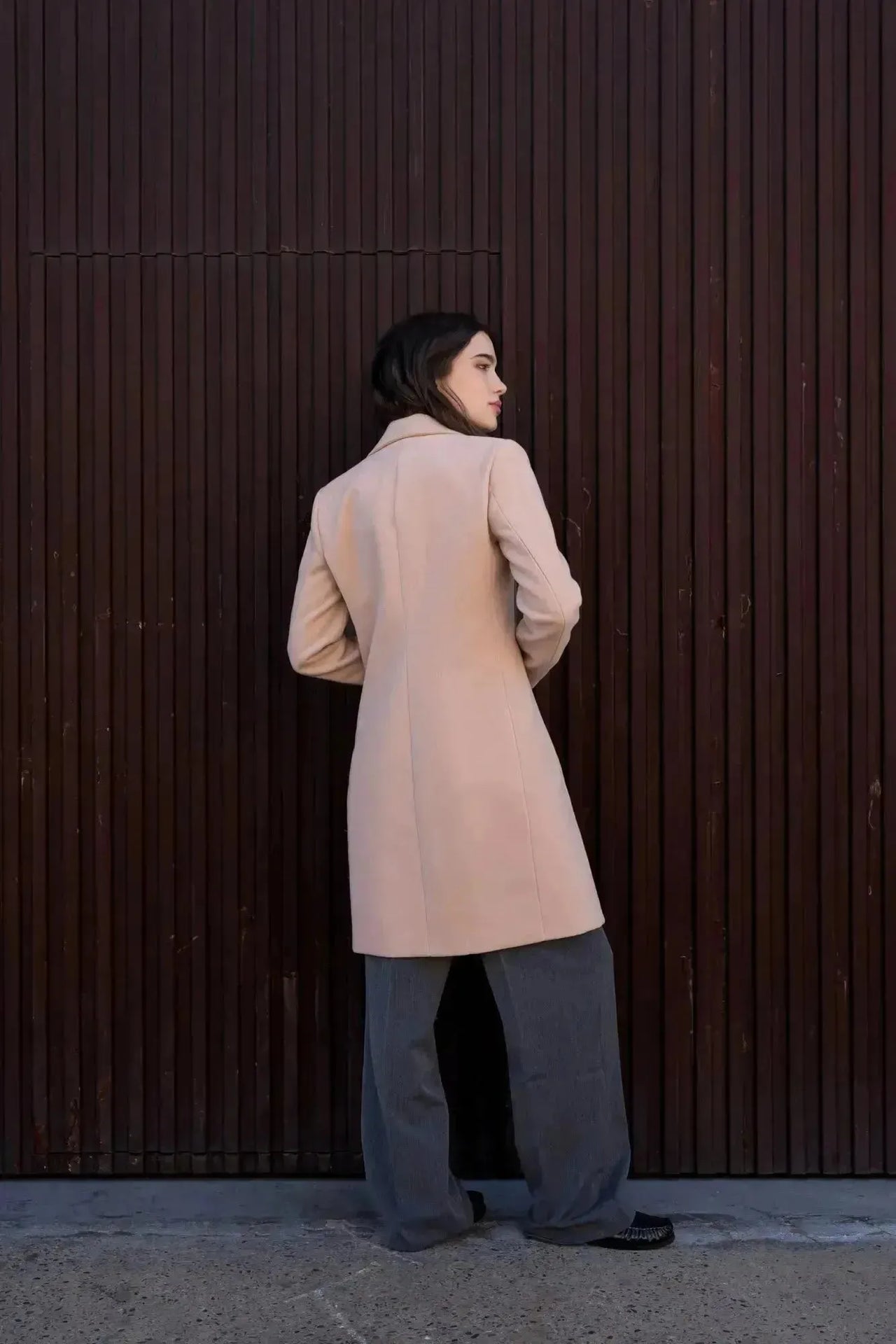 Vue arrière d'un manteau beige femme long élégant sur un modèle, avec une ambiance moderne.