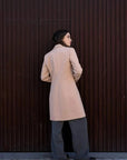 Vue arrière d'un manteau beige femme long élégant sur un modèle, avec une ambiance moderne.