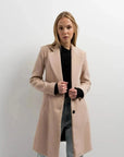 Manteau beige femme long élégant sur un modèle avec un ensemble décontracté, ajoutant une touche de chic à la garde-robe.