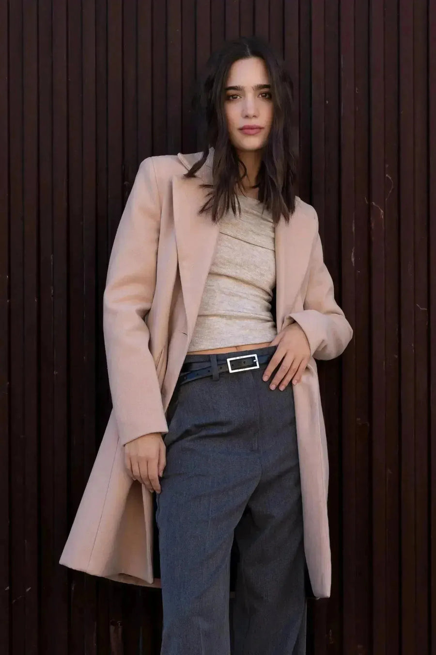 Manteau beige femme long élégant porté par une modèle avec un pull beige et un pantalon gris, parfait pour l'hiver.