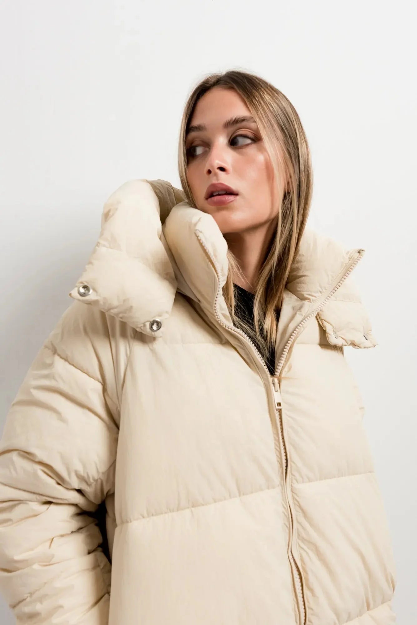 Image d’un manteau matelassé oversize beige avec col haut et fermeture éclair