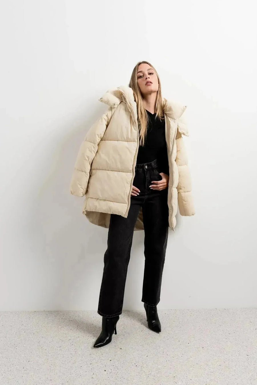 Manteau très chaud femme oversize beige à capuche, chic et confortable pour l'hiver, modèle porté par une femme, avec une pose élégante.