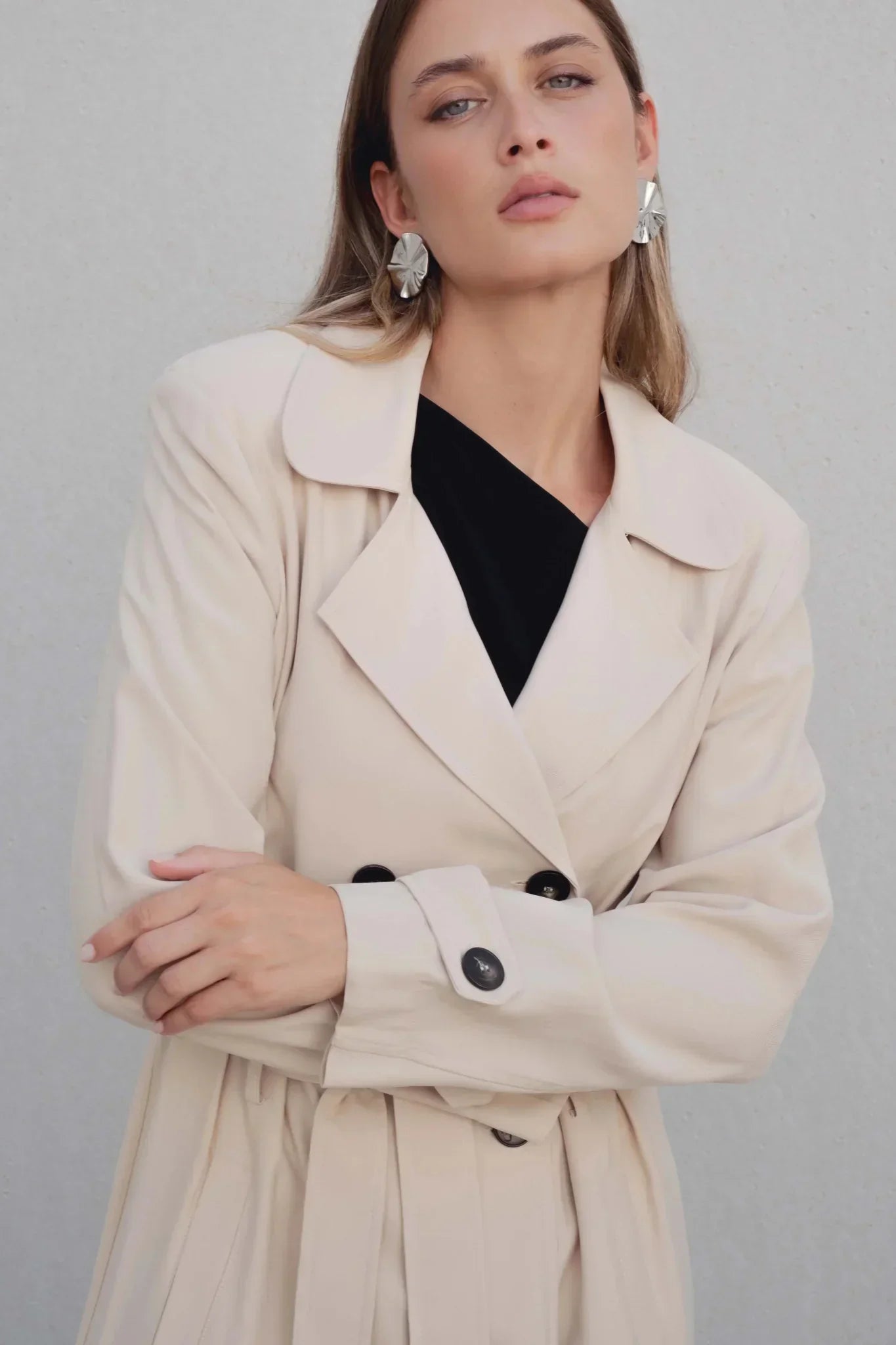 Gros plan sur une femme en manteau trench femme fluide long beige, mettant en valeur le col classique et les détails de la veste.