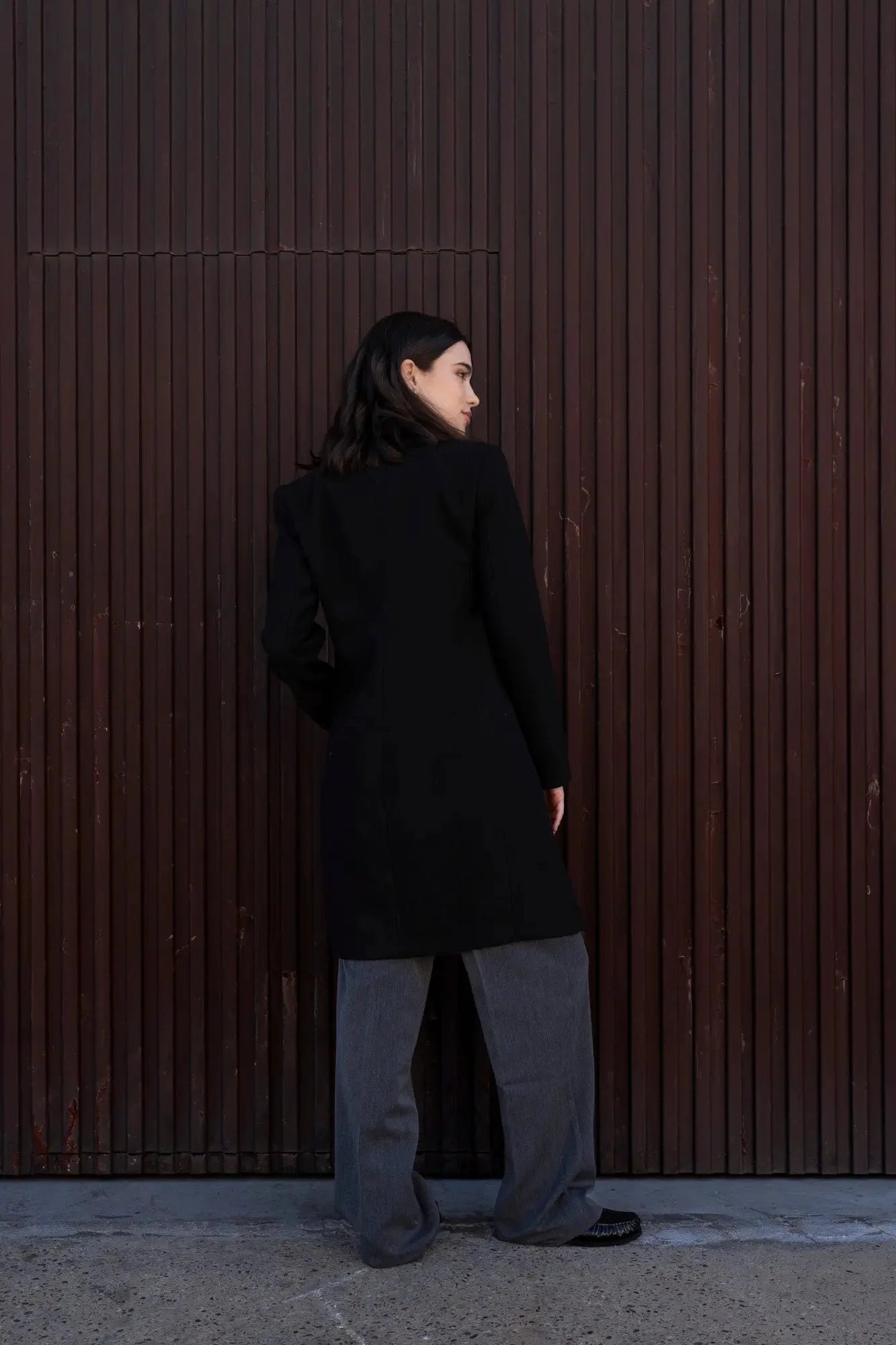Femme portant un manteau avec col revers en noir et pantalon gris