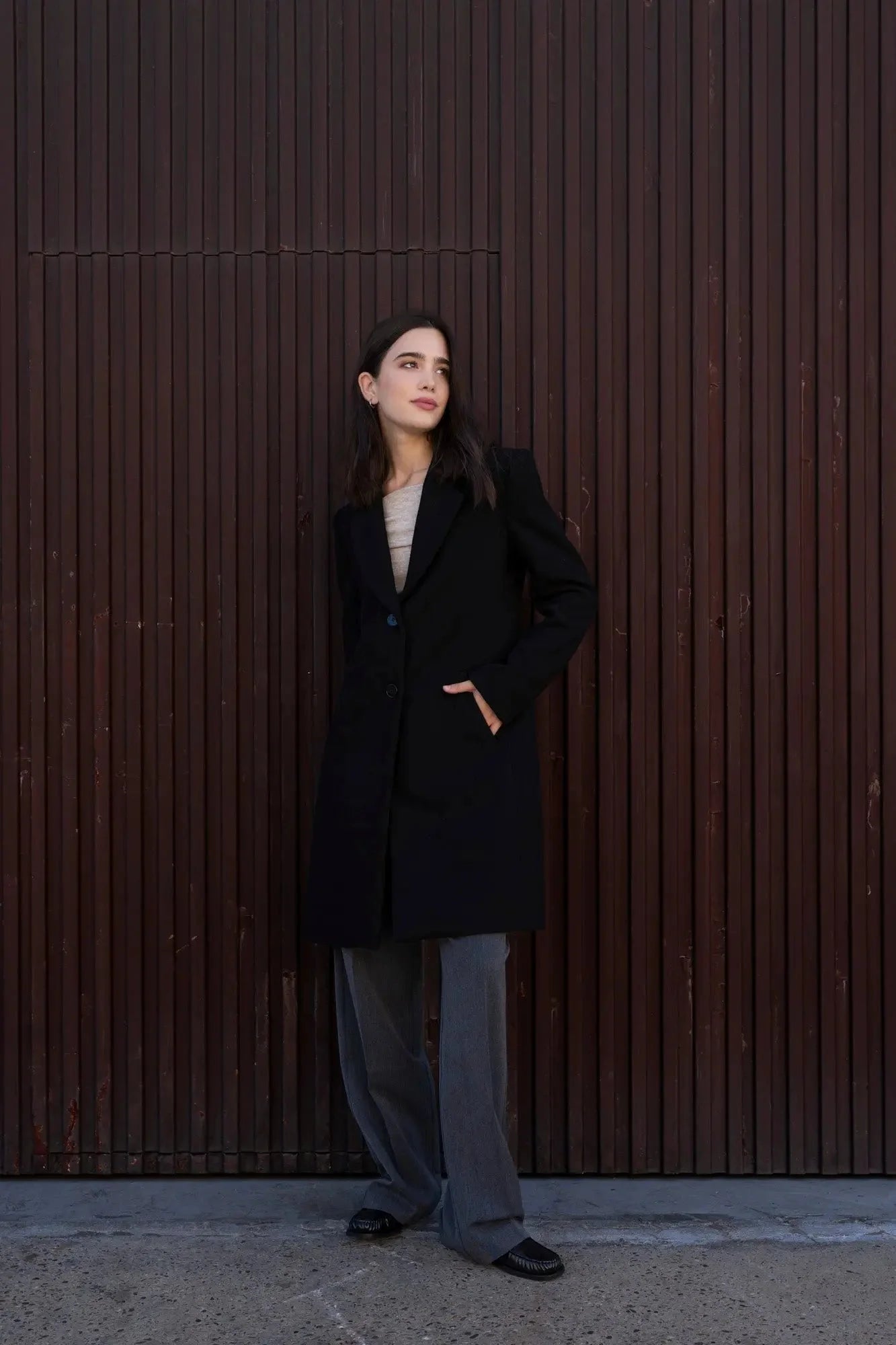 Femme portant un Manteau avec collier de revers, veste noire, pantalon gris et chaussures noires