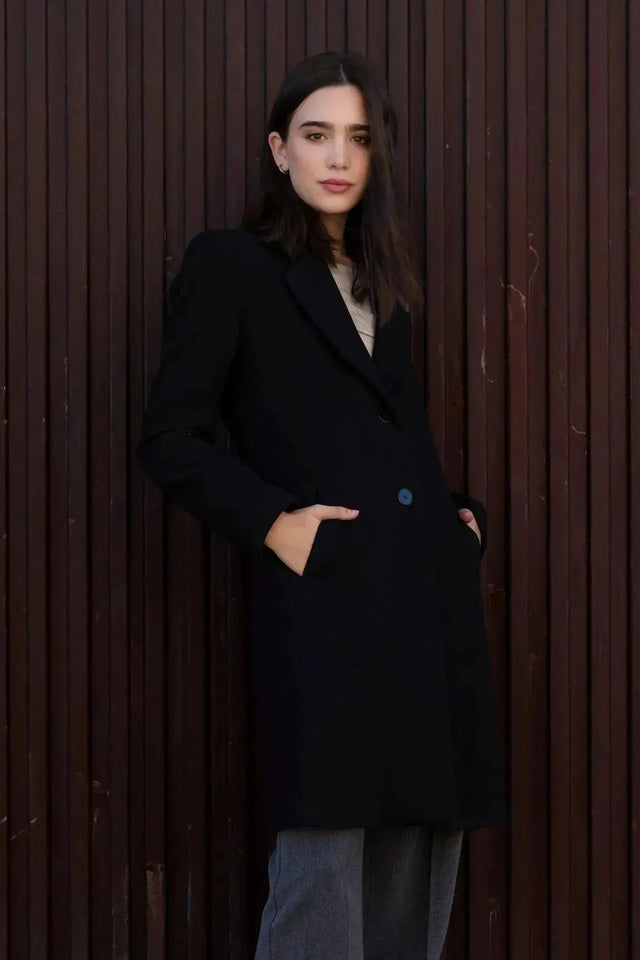Manteau Long Chaud Femme: Élégant manteau noir à col de revers sur une femme, parfait pour l'hiver, mettant en valeur le style et le confort.