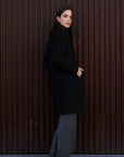 Manteau Long Chaud Femme: Femme souriante en manteau long noir, avec une touche de sophistication pour un look d'hiver tendance.