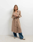 Femme posant dans un manteau trench oversize long marron clair, démontrant la polyvalence du trench coat femme avec un jean ample.
