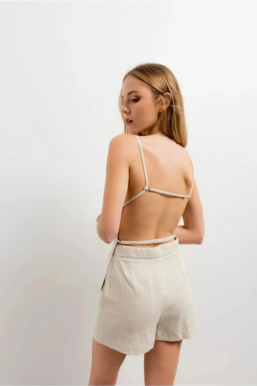 Femme vue de dos avec une mini jupe short en lin naturel, soulignant le design léger et respirant de cette pièce tendance.