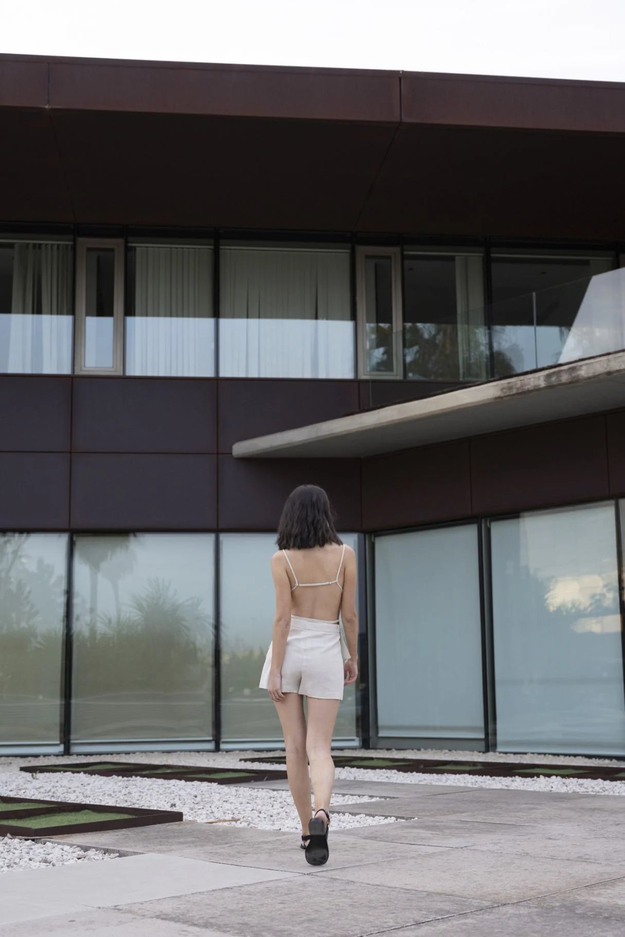 Vue de dos d&#39;un modèle dans une mini jupe short en lin naturel, marchant à l&#39;extérieur avec un style estival.