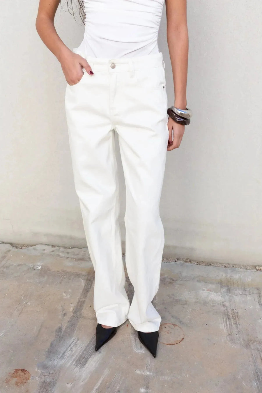 Mannequin posant avec un pantalon blanc femme à jambe large, stylé avec des talons, montrant un look affirmé.