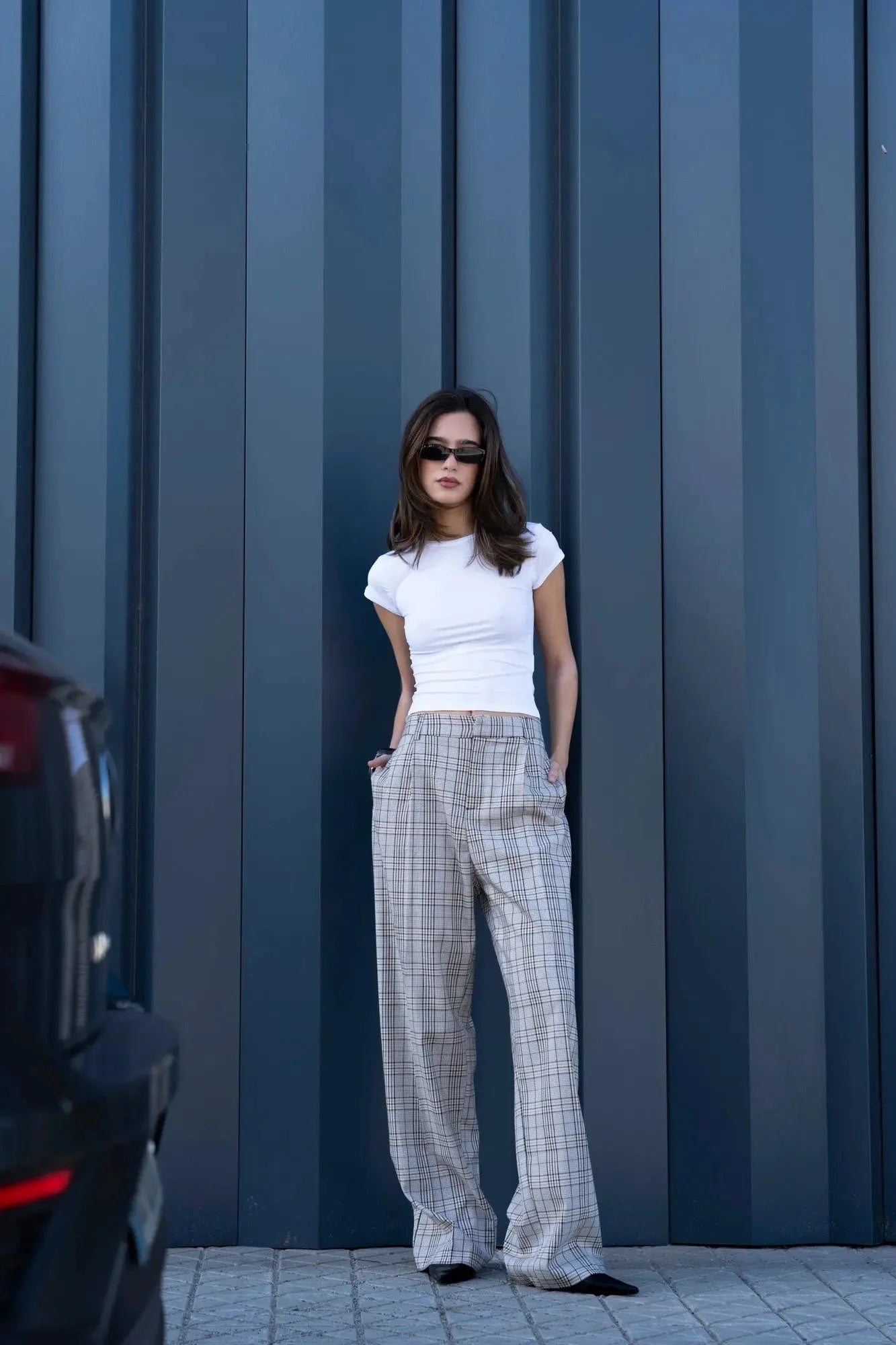 Femme élégante portant un pantalon à carreaux et un t-shirt blanc, style chic