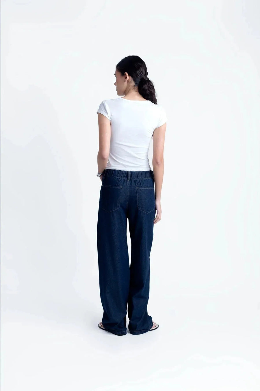 Vue arrière du modèle en tee shirt blanc femme fluide en polyamide, portant un pantalon en denim, confort et style réunis.