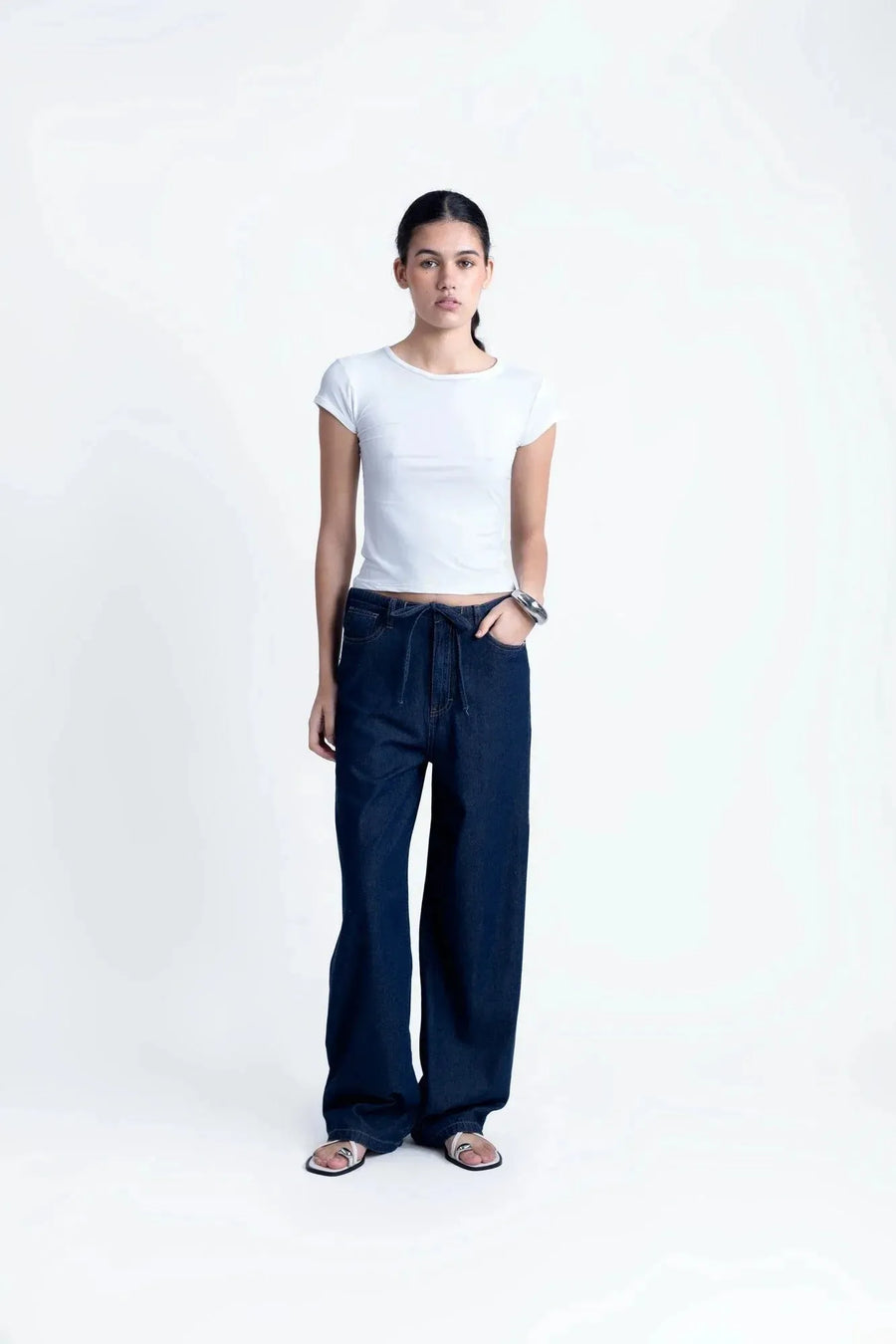 Modèle féminin portant un tee shirt blanc femme fluide en polyamide, avec un pantalon en denim, affichant un style élégant.