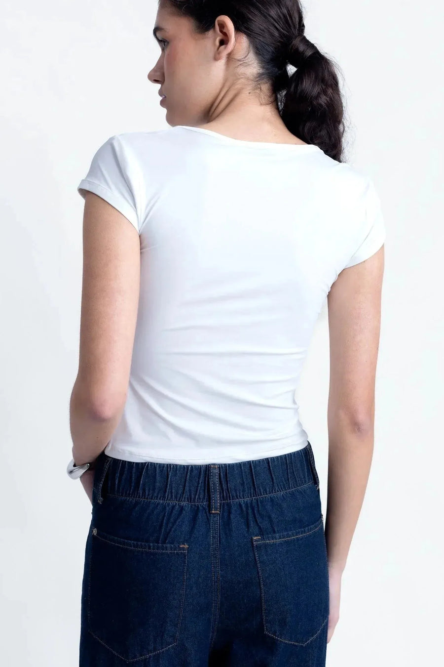 Modèle féminin montrant le dos dans un tee shirt blanc femme fluide, mettant en avant la coupe élégante et le confort optimal.