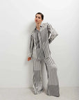 Modèle posant en pantalon fluide femme noir et blanc rayé, combiné avec une chemise oversize pour un look chic et décontracté.