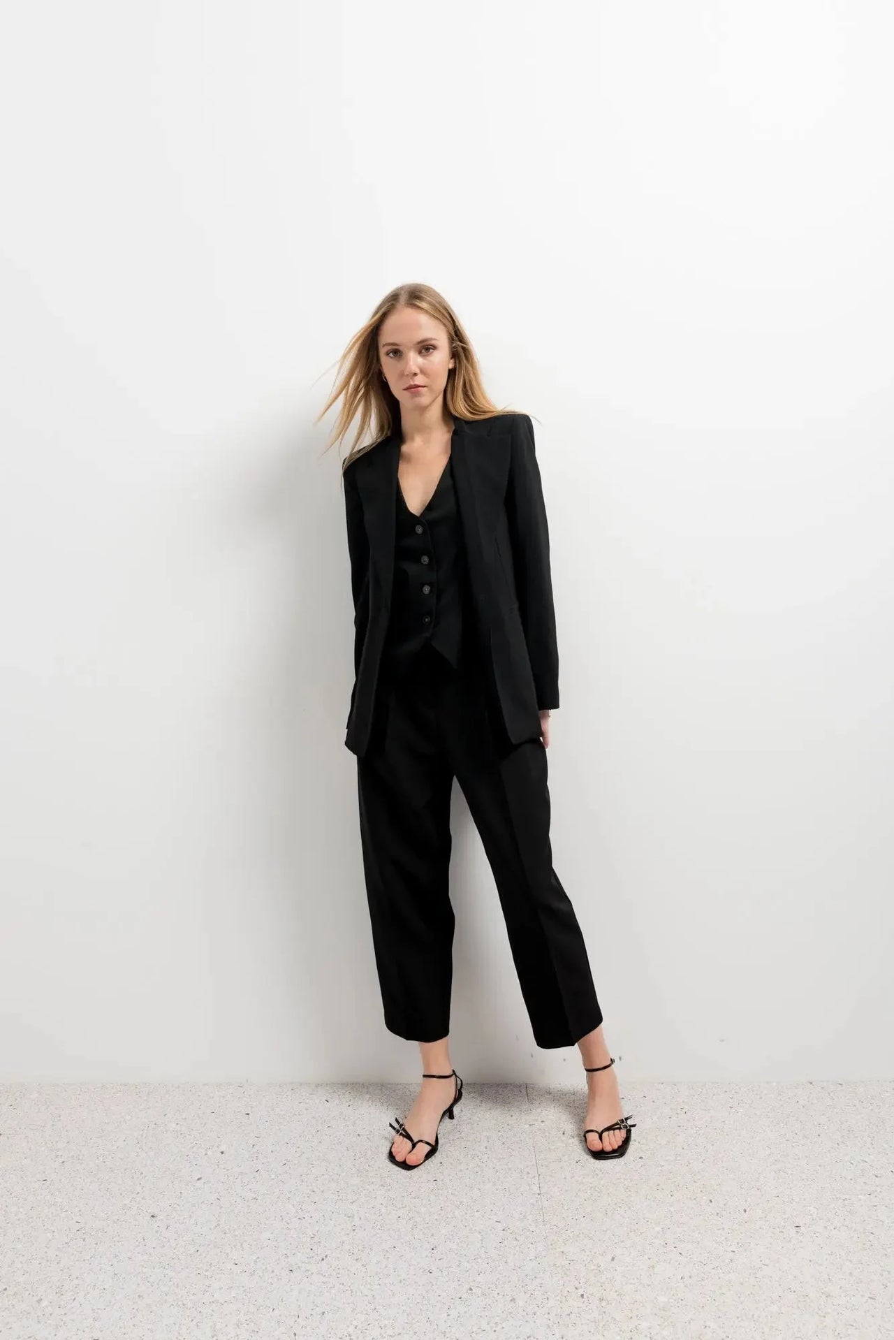 Femme portant un pantalon court plissé taille basse noir avec un blazer, mettant en valeur le pantalon court noir femme dans une tenue chic.