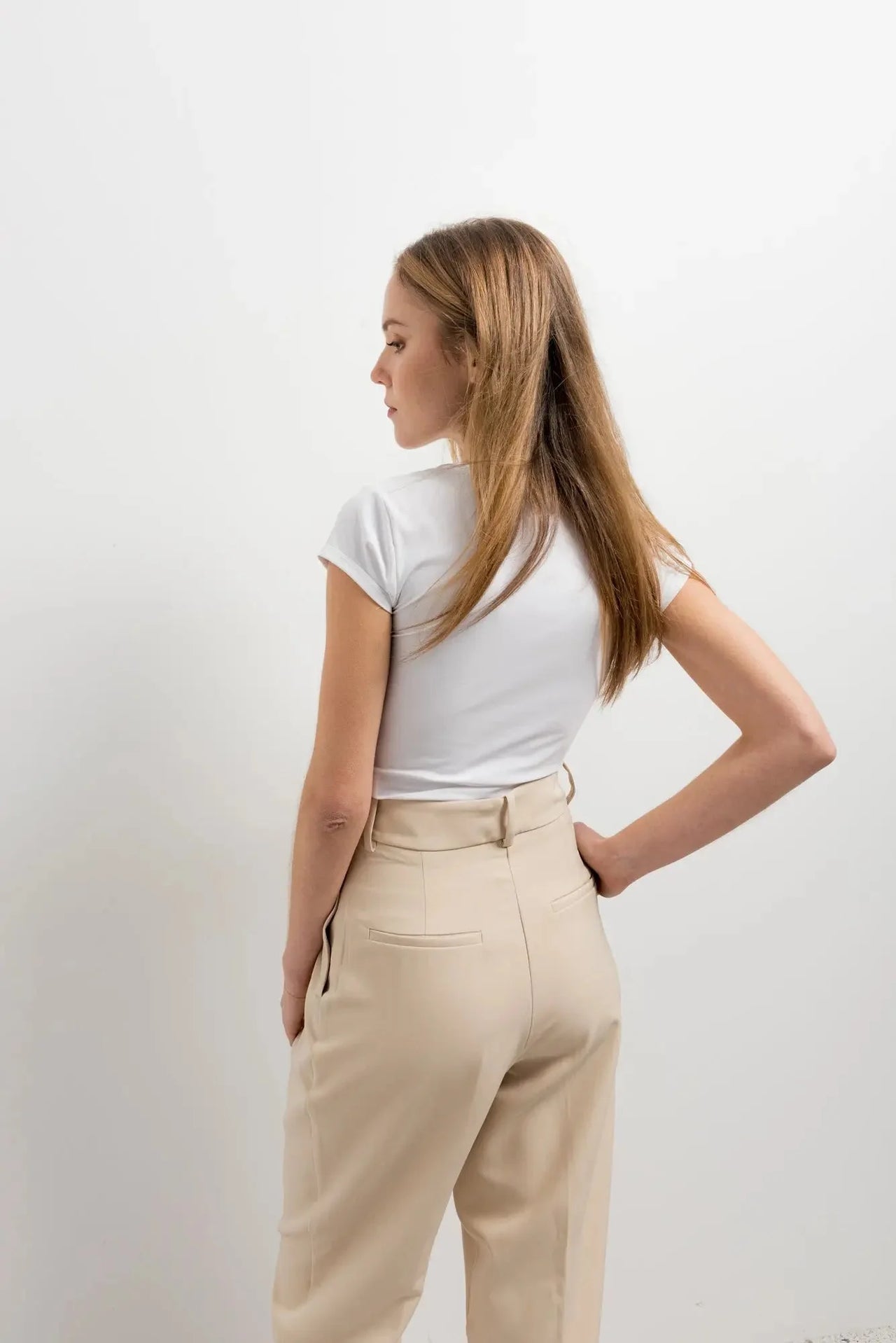 Vue arrière d'une femme en t-shirt blanc et pantalon court plissé taille basse beige, montrant le style moderne du pantalon court noir femme.