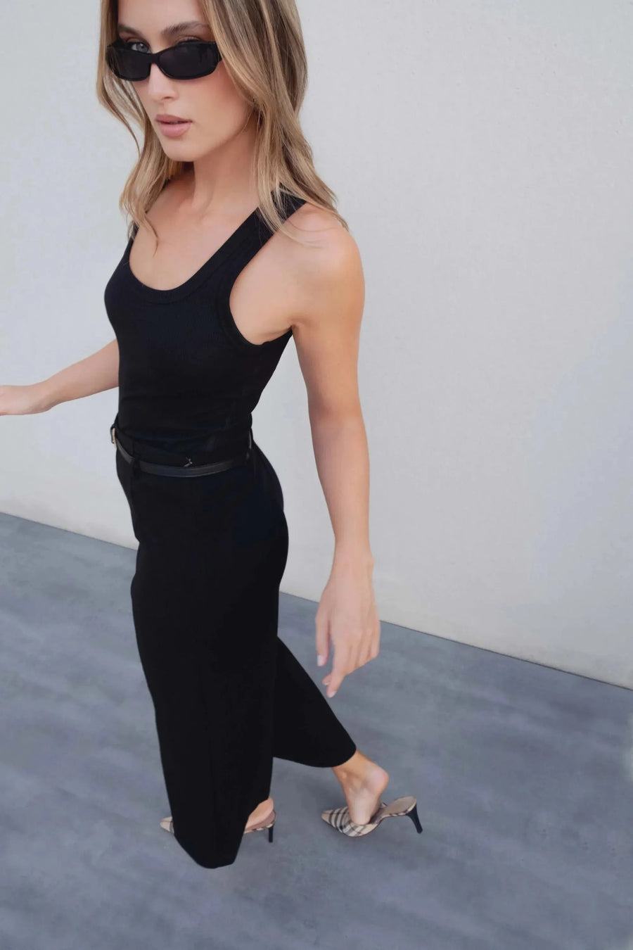 Femme portant un pantalon culotte taille haute jambe large noir boucle métallique, associé à un haut noir et des chaussures à talons, idéal pour un look chic.