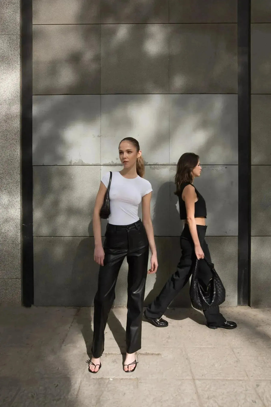 Deux modèles portant respectivement un pantalon imitation cuir femme et un haut tendance, illustrant la polyvalence du Pantalon Effet Cuir Noir Élégant.