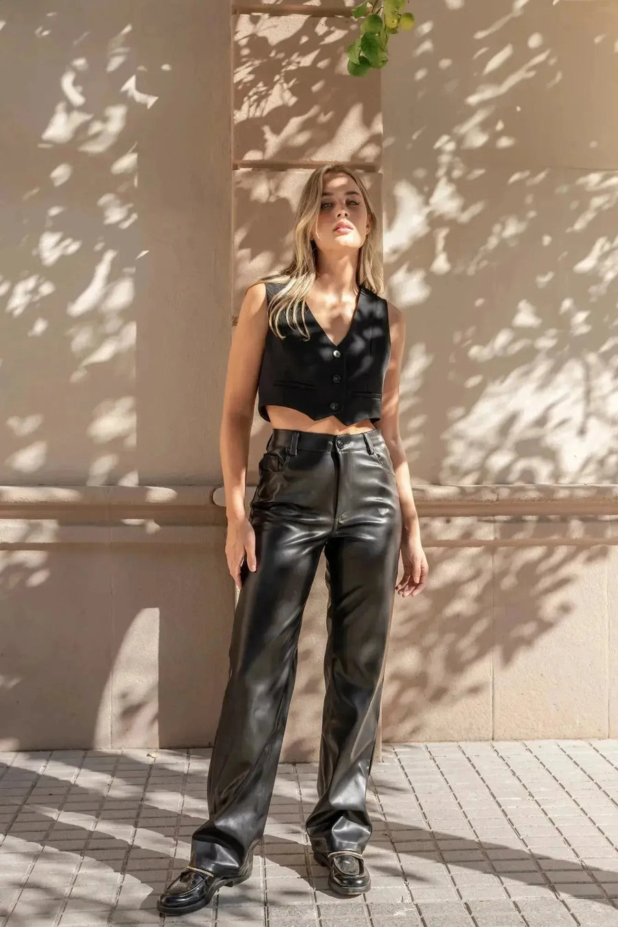Modèle mettant en avant le Pantalon Effet Cuir Noir Élégant, idéal pour un style tendance avec une top noir. Parfait pour les femmes cherchant un pantalon imitation cuir femme.