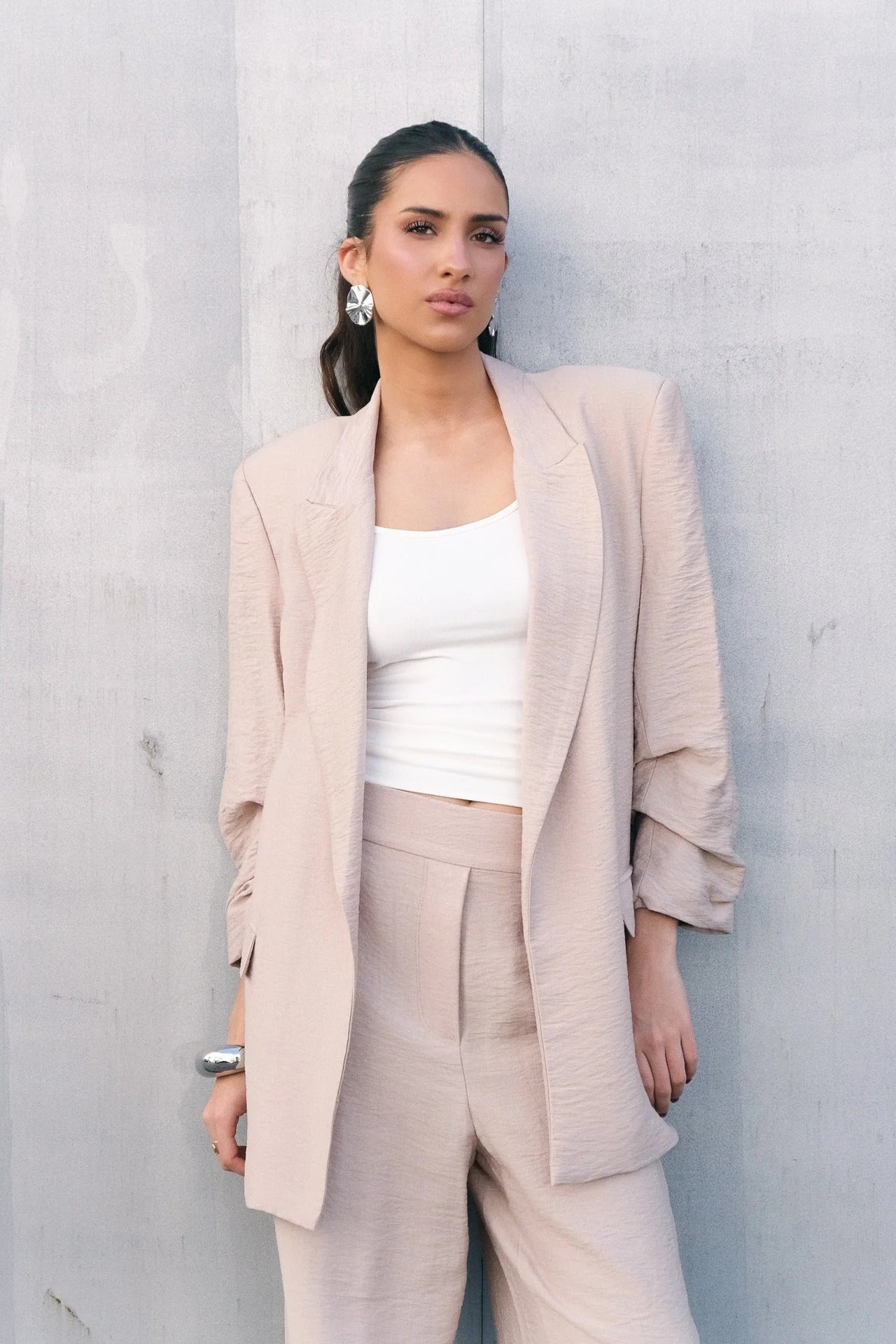 Femme portant un pantalon fluide beige et blazer assorti, look élégant et chic