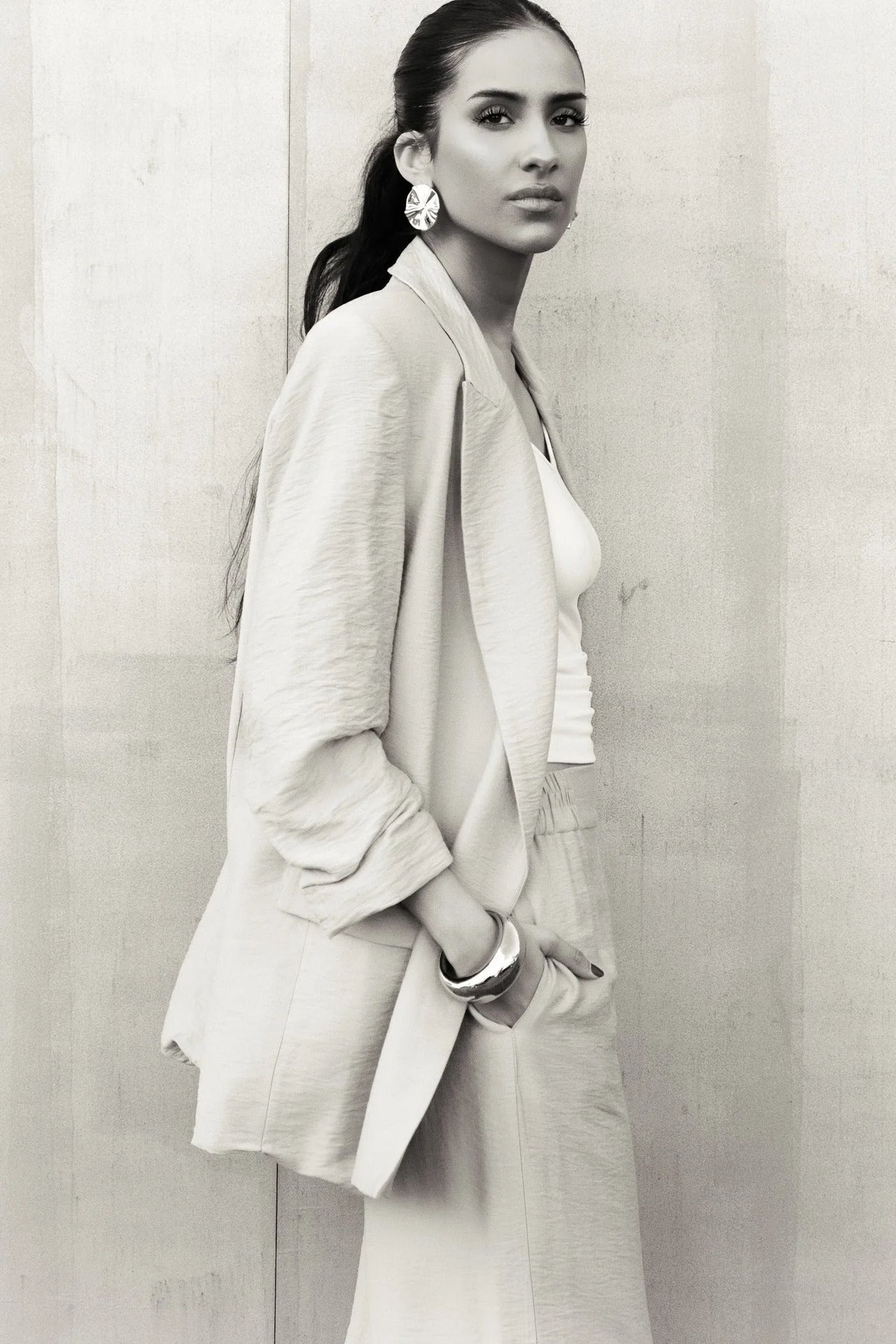 Femme portant un pantalon fluide beige et un blazer assorti, look élégant et chic