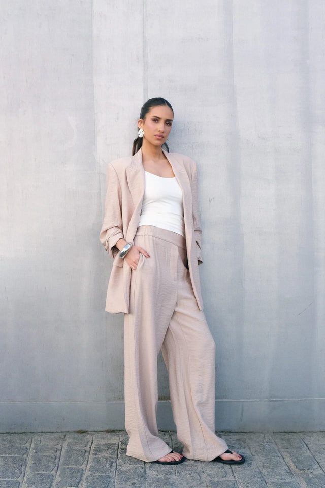 Femme portant un ensemble pantalon fluide beige et blazer assorti, blanc et noir