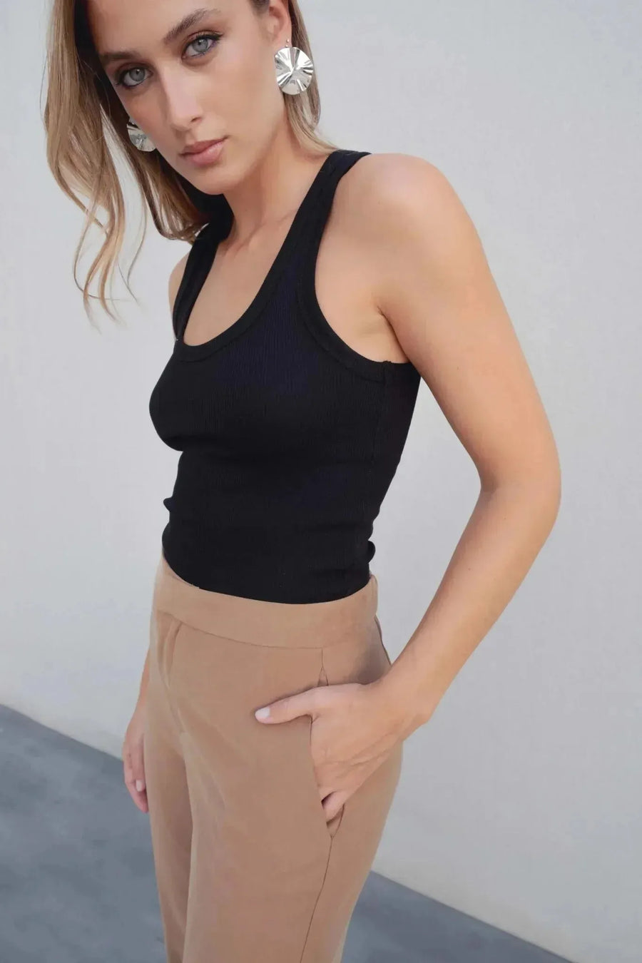 Pantalon fluide femme beige associé à un haut noir, détails sur la coupe confortable et chic.