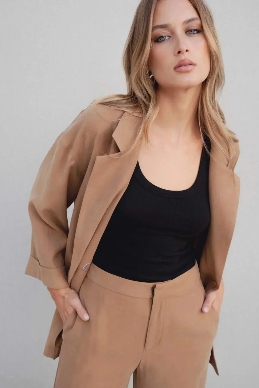 Modèle avec pantalon fluide femme beige et blazer camel, style moderne et tendance.