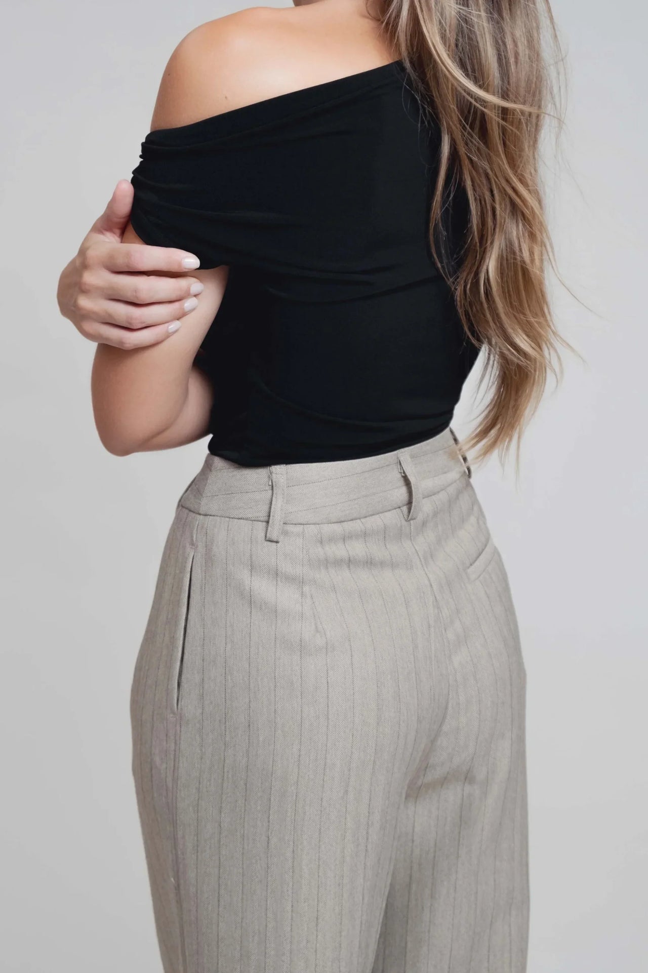 Détails du dos d'un haut noir porté avec un pantalon fluide à rayures, parfaite illustration du pantalon fluide femme taille haute.