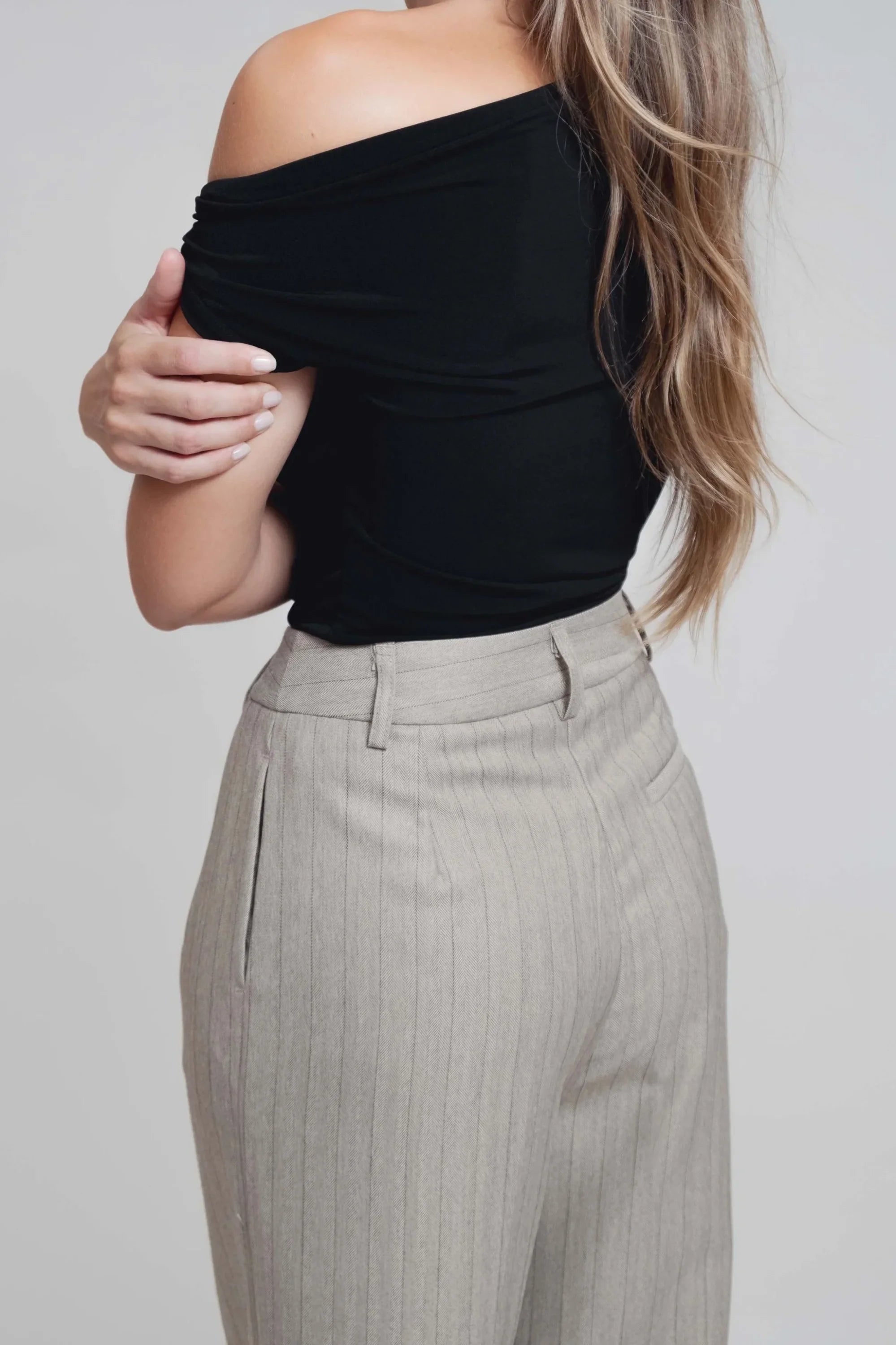 Femme portant un pantalon tailleur rayures fines et un haut noir en tissu tailleur doux