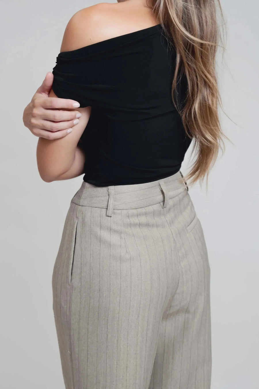 Détails du dos d'un haut noir porté avec un pantalon fluide à rayures, parfaite illustration du pantalon fluide femme taille haute.