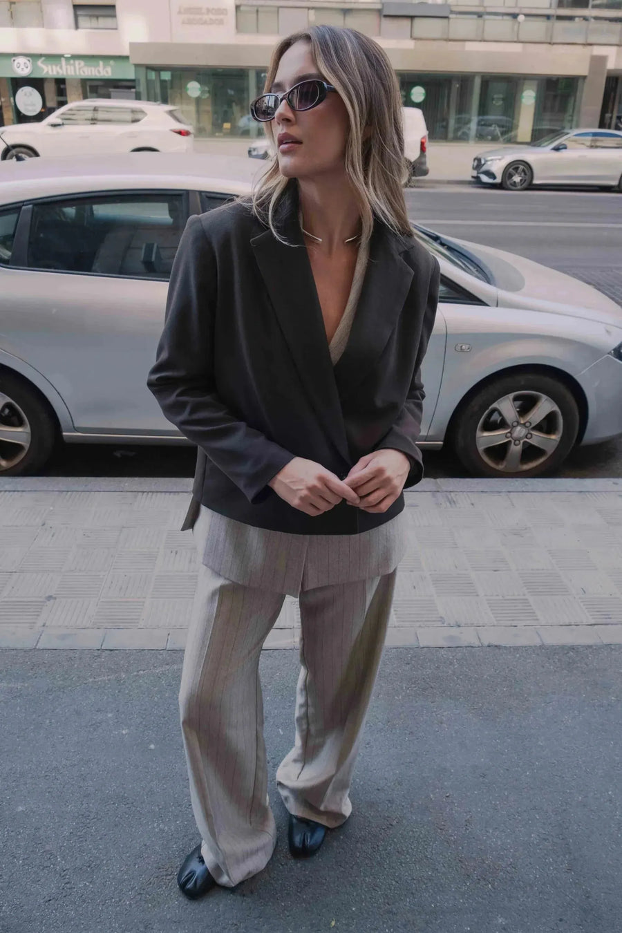 Femme portant un pantalon fluide à rayures, chic et élégant, avec un blazer assorti, illustrant le pantalon fluide femme taille haute.
