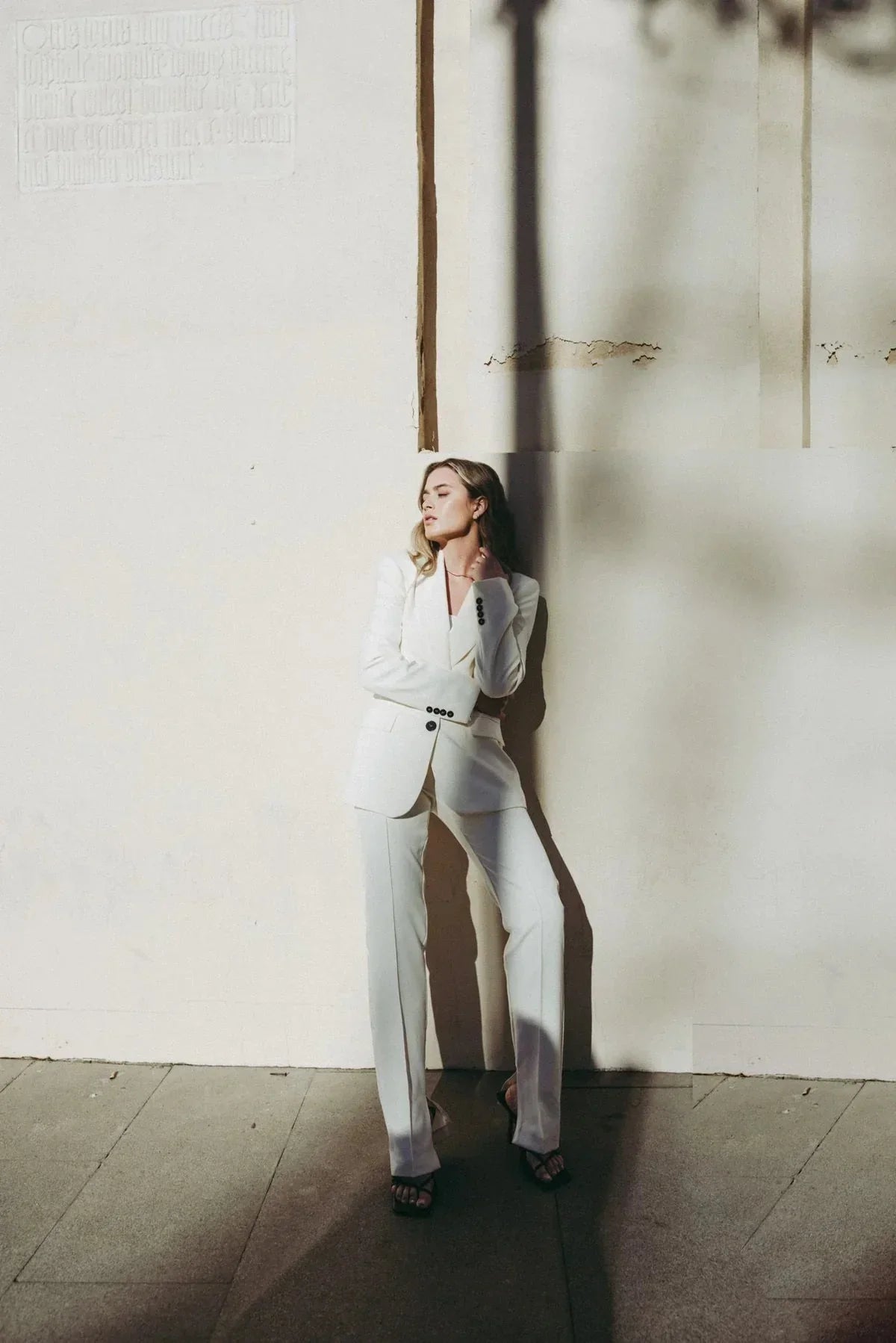 Femme portant un pantalon habillé écru lumineux avec ceinture noire et talons ouverts