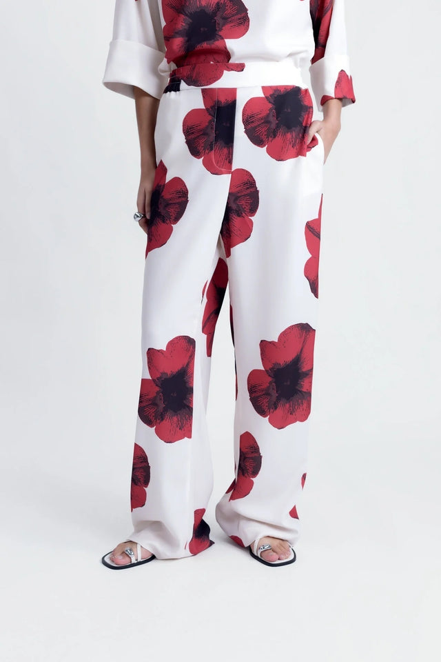 Détail du bas d'un pantalon habillé fluide – Coupe droite moderne – Blanc à fleurs rouges – Matière légère, représentant le pantalon motif femme.