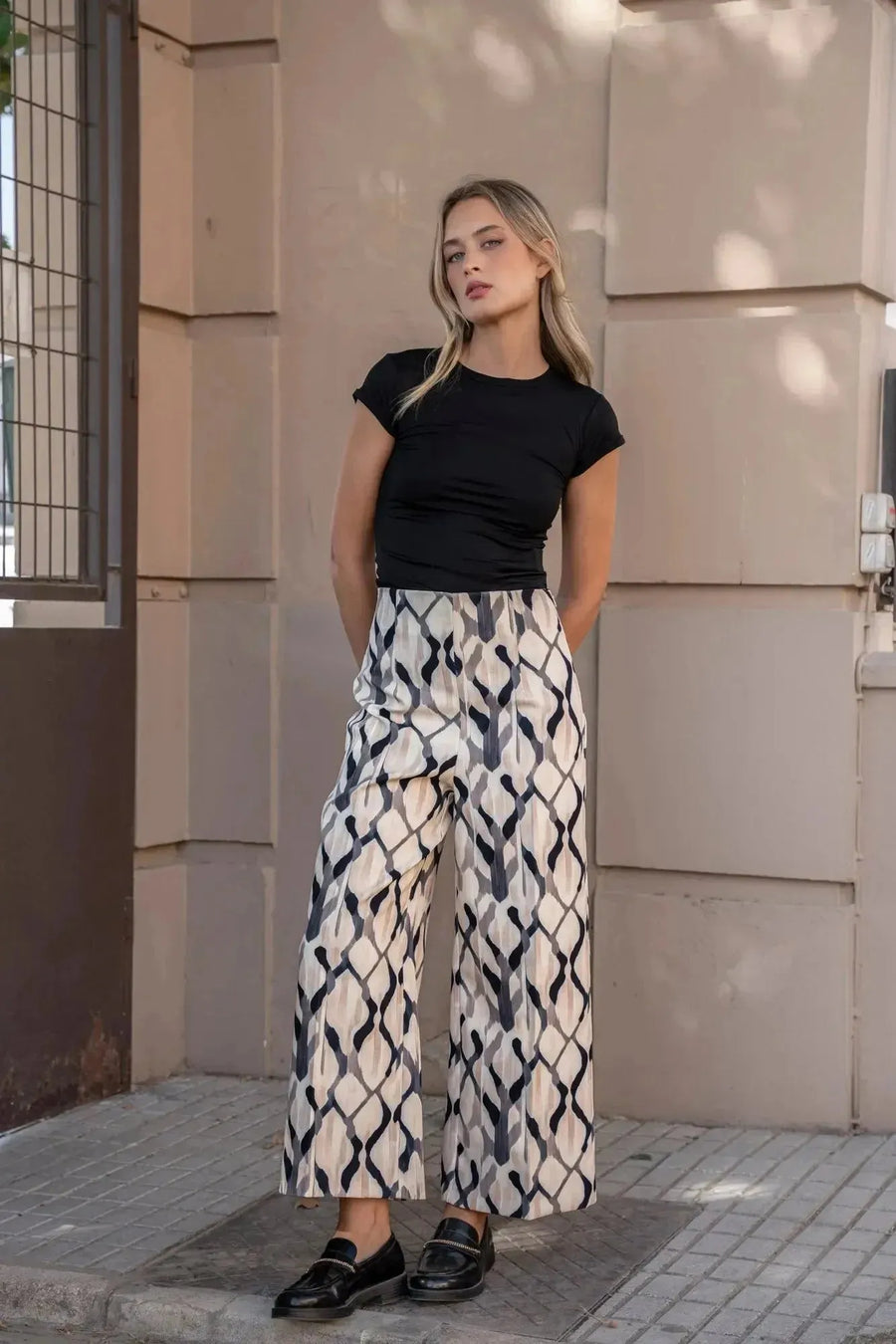 Pantalon motif femme palazzo imprimée, image d'un modèle portant un t-shirt noir et le pantalon motif femme, style élégant et confortable avec poches.