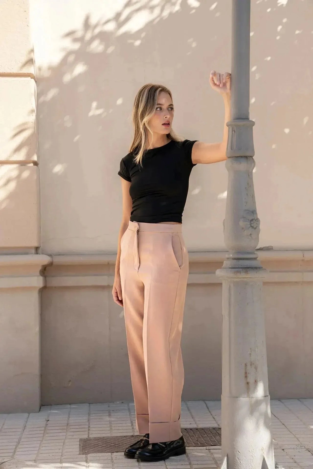 Femme dans un pantalon femme pince à revers, regardant vers la droite, près d'un lampadaire.